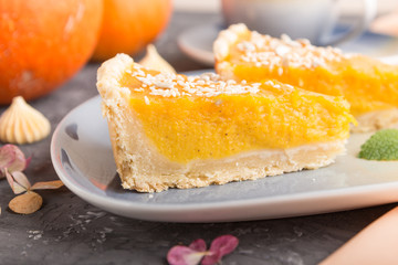 Two pieces of traditional american pumpkin pie with cup of coffee on a black concrete background. side view, selective focus.