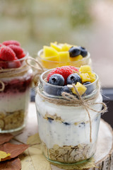 Delicious yogurt pudding with сhia seeds, oats, berries and fruit in glass jars for healthy food on a wooden tray.