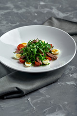 Tasty italian salad of beef tongue with eggs, arugula, tomato, spices and sauce