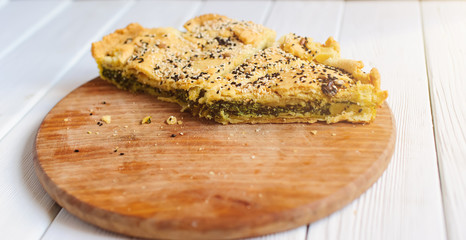 Homemade spinach french pie on a white wooden board