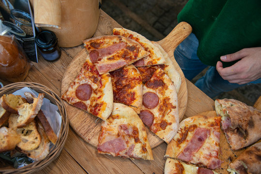 Hot sliced crunchy pepperoni, bacon, tomato, cheese pitsa on counter for sale.