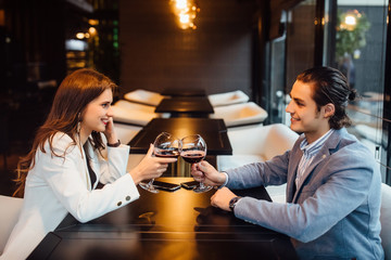 Dating in the cafe. Romantic couple holding glass of wine and enjoying in conversation.
