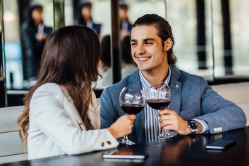 Couple making a toast with red wine while sitting in restaurant.