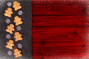 Gingerbread cookies and snowflakes in decoration on red wooden table, directly above.