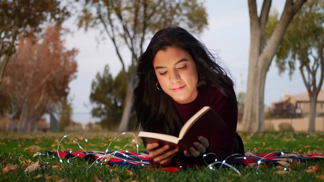 An attractive young woman opening the pages of a book and reading a chapter of the story SLIDE RIGHT.