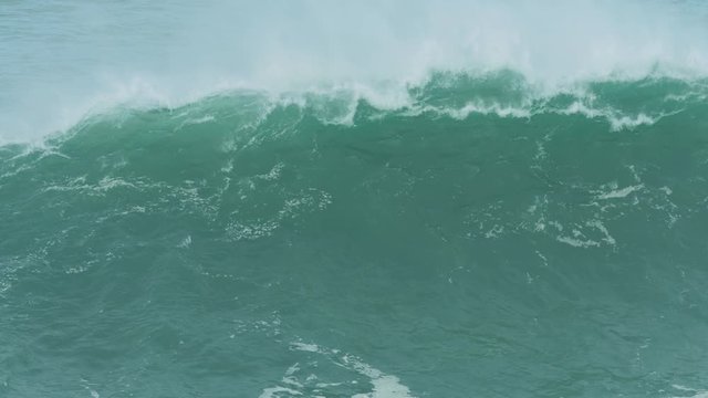 60fps slow motion of a huge wave breaking off the coast of Nazare, Portugal