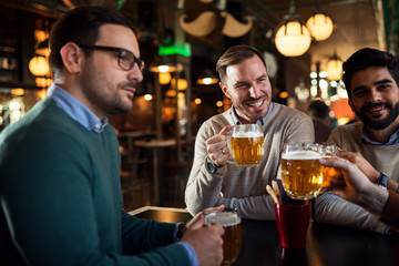 Happy group of friends drinking beer in pub