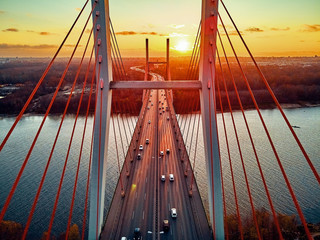 Obraz premium Beautiful panoramic aerial drone view to cable-stayed Siekierkowski Bridge over the Vistula river and Warsaw City skyscrapers, Poland in gold red autumn colors in November evening at sunset