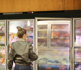 Fototapeta na wymiar Woman choosing frozen food from a supermarket freezer 