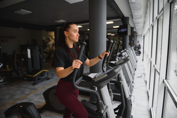 Fototapeta na wymiar attractive young woman runs on a treadmill, is engaged in fitness sport club