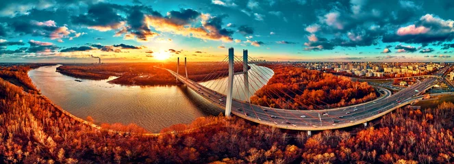 Foto op Plexiglas Beautiful panoramic aerial drone view to cable-stayed Siekierkowski Bridge over the Vistula river and Warsaw City skyscrapers, Poland in gold red autumn colors in November evening at sunset © udmurd