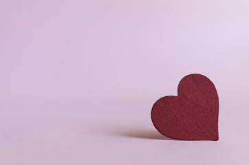 red heart shape wooden piece on pink background