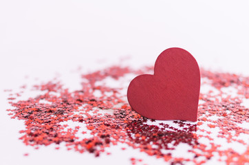 Fototapeta premium red heart shape wooden piece on pink background with red glitter
