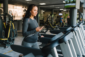 Portrait of Fitness woman running on treadmill in gym listening to music.exercising concept.fitness and healthy lifestyle.