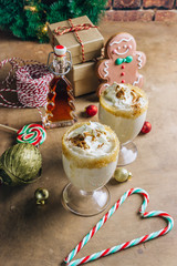 New Year or Christmas Eggnog cocktail - hot winter or autumn drink with milk, eggs and dark rum, sprinkled with cinnamon and nutmeg in a glass on wooden background, festive decoration