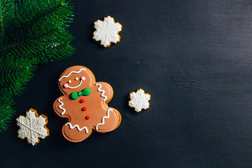 Christmas composition. Xmas cookies, Gingerbread man, fir branches on black background. Flat lay, top view, with copy space.