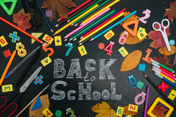 Back to school concept. School and office supplies on blackboard background.