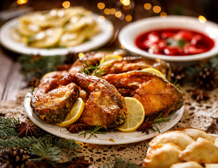 Christmas carp, fried carp fish slices on a ceramic plate on the holiday table, close up. Traditional christmas eve dish. Polish Christmas - obrazy, fototapety, plakaty