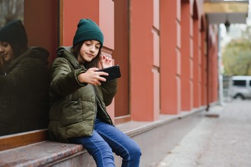 stylish beautiful teen girl on the street in a hat and jacket