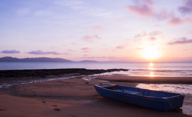 Small boat on an empty beach at sunset