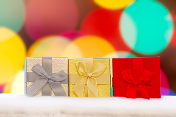 Colourful Gift boxes Presents on snow with a bokeh Background