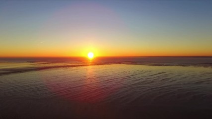 Drone footage over Shoeburyness garrison during sunrise in December birds flying tide out  bright sun stable