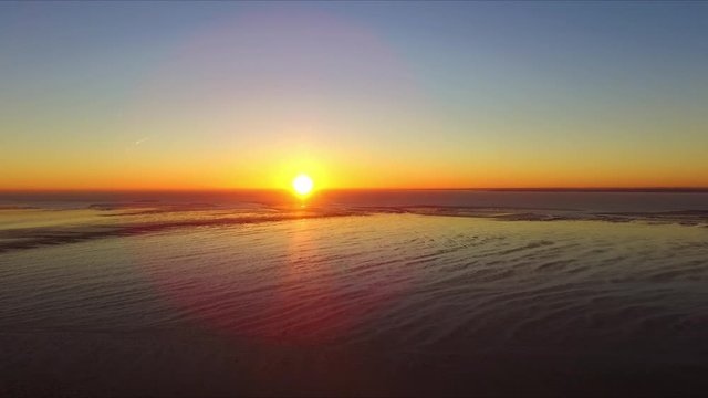 Drone footage over Shoeburyness garrison during sunrise in December birds flying tide out  bright sun stable