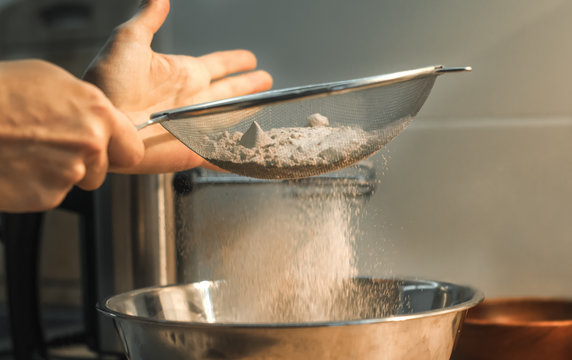 Girl sprinkles flour through a sieve. Sift flour. lifestyle food