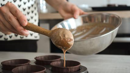 Preparation for baking a healthy chocolate fitness dessert of brownie or cupcakes without sugar.A female hand pours the dough into a baki