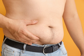 Naklejka premium Overweight man touching fat on his belly, closeup. Weight loss concept
