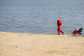 Santa Claus in swimming suit walking along the beach