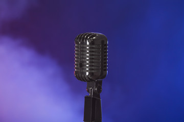 Fototapeta premium Retro microphone on dark color background with smoke
