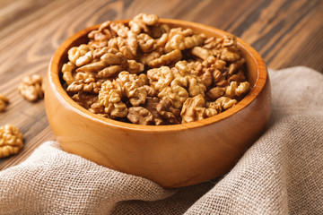 Bowl with tasty walnuts on wooden table