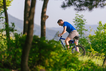 Adventurous mountain biker riding his bike fast through the woods ( forest ) while enjoying the green nature.