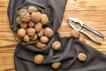 Basket with tasty walnuts and nutcracker on wooden table