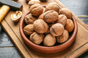 Plate with tasty walnuts on wooden board