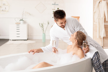 Obraz premium Happy young couple drinking champagne in bathroom