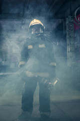 Portrait of a female firefighter wearing a helmet and all safety equipment a while holding a...
