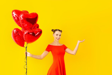 Beautiful young woman with heart-shaped balloons on color background