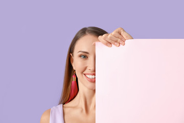 Naklejka premium Beautiful young woman with blank poster on color background
