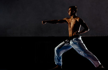Fototapeta na wymiar Karate martial arts fighter in white kimono in the gym