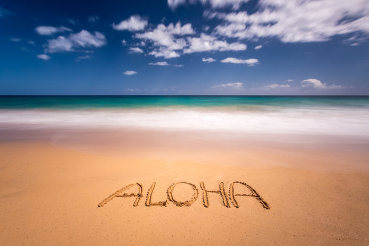 The word aloha written on the sand of a beach in Kauai, Hawaii