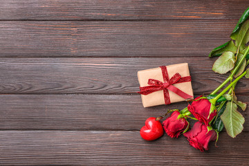 Gift for Valentine's Day, rose flowers and red heart on wooden background