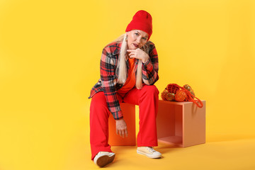 Fashionable mature woman on color background