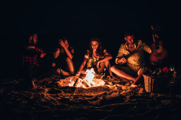 Friends roasting sausage at the beach in the night