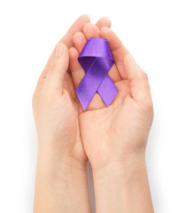 Female hands with purple ribbon as symbol of World Cancer Day on white background