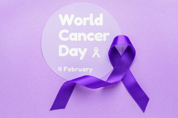 Paper with text WORLD CANCER DAY and purple ribbon on color background