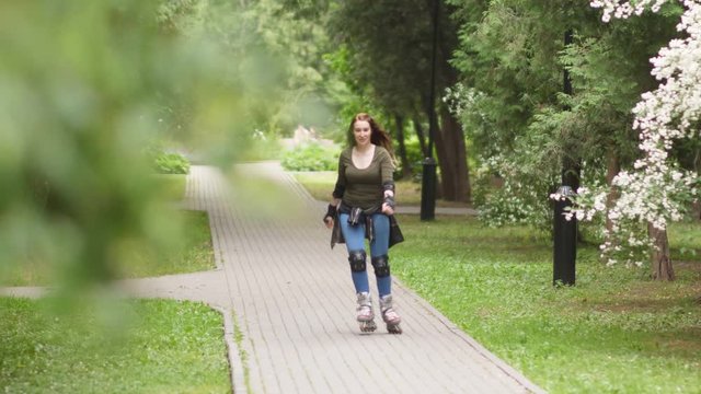 Young woman is riding on rollerblades in the park