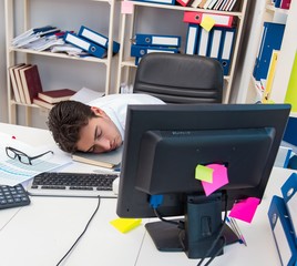 Businessman working in the office with piles of books and papers
