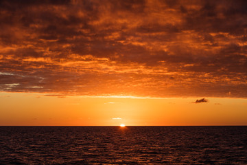 Naklejka na ściany i meble The very last light of day peeks over the horizon in the Caribbean Sea.